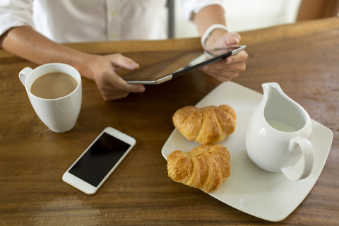 Woman at breakfast table using tablet stock photo