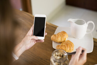 Woman at breakfast table using cell phone - KNTF00786