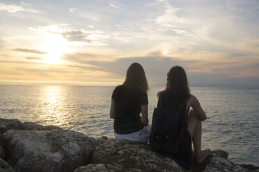 Indonesia, Bali, two women watching the sunset over the ocean - KNTF00792