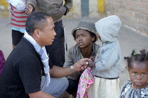 Madagaskar, Fianarantsoa, Sozialarbeiter im Gespräch mit einer obdachlosen jungen Mutter und ihrem Kind - FLKF00783