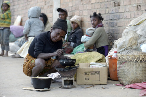 Madagaskar, Fianarantsoa, Obdachlose Frau kocht Reis auf der Straße - FLKF00787