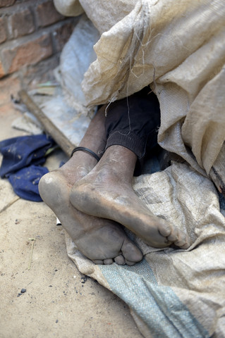 Madagaskar, Fianarantsoa, Nackte Füße eines unter Lumpen schlafenden Obdachlosen, lizenzfreies Stockfoto