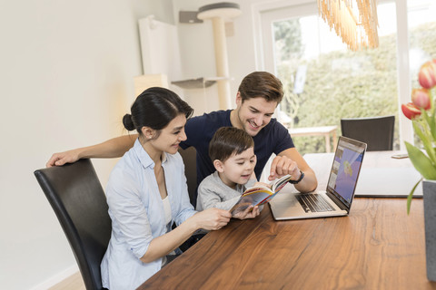 Family with laptop and guidebook planning vacation at home stock photo