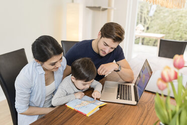 Familie mit Laptop und Reiseführer bei der Urlaubsplanung zu Hause - SHKF00723