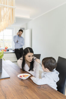 Mutter und Sohn beim Frühstück mit dem Vater am Telefon im Hintergrund - SHKF00728