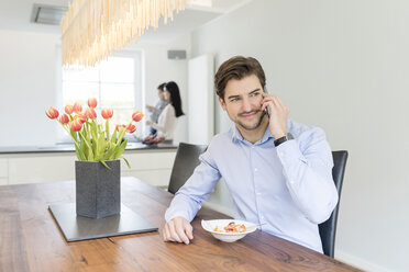 Mann am Telefon mit Mutter und Sohn im Hintergrund - SHKF00731