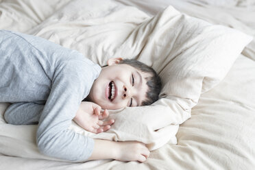 Glücklicher Junge im Bett liegend - SHKF00735