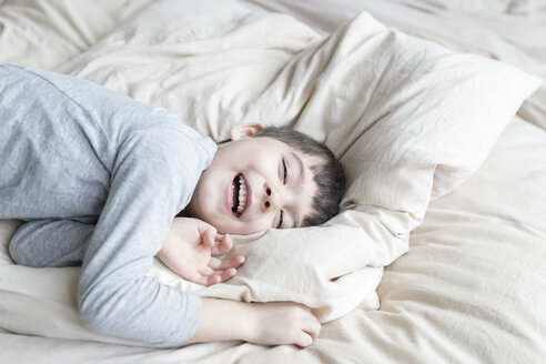 Glücklicher Junge im Bett liegend - SHKF00735