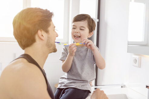 Happy father and son brushing teeth together in bathroom - SHKF00742