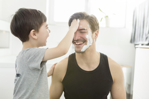 Playful son applying shaving foam on father's face stock photo