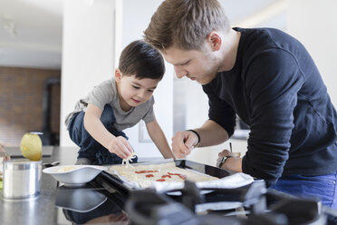 Vater und Sohn bereiten gemeinsam eine Pizza in der Küche zu - SHKF00752