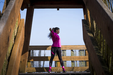 Woman stretching on wooden bridge - SIPF01446