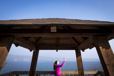 Woman in sportswear taking a selfie on observation terrace by the sea - SIPF01449