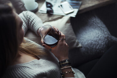 Young woman with glass of coffee relaxing on couch at home - NAF00061
