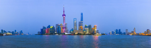 China, Shanghai, Panoramablick auf die Skyline von Pudong mit dem Huangpu-Fluss im Vordergrund in der Dämmerung, lizenzfreies Stockfoto