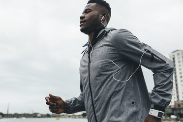 Young man running with earbuds and smartwatch - BOYF00668