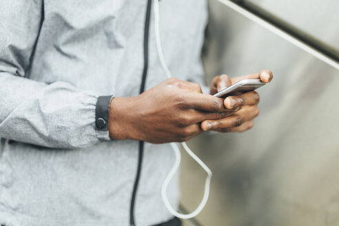 Nahaufnahme eines Sportlers, der ein Mobiltelefon benutzt - BOYF00676