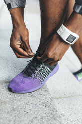 Close-up of athlete wearing smartwatch tying shoes - BOYF00683