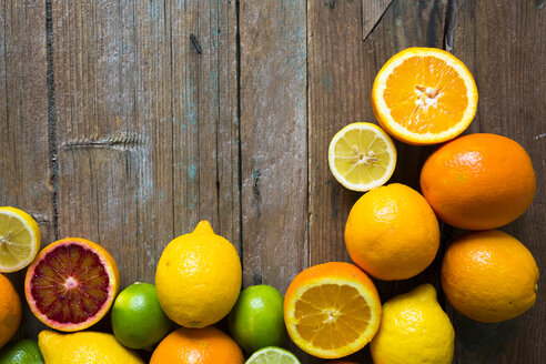 Aufgeschnittene und ganze Zitronen, Orangen und Limetten auf Holz - GIOF02238