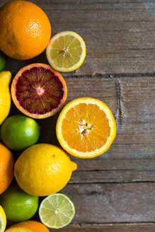 Aufgeschnittene und ganze Zitronen, Orangen und Limetten auf Holz - GIOF02240