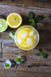 Glass of orange juice, limes, lemon and ice cubes - GIOF02245