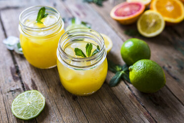 Zwei Gläser mit Orangensaft, Limetten, Zitrone und Eiswürfeln - GIOF02248