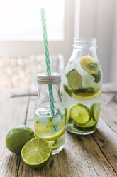 Glasflaschen mit aufgegossenem Wasser mit Zitrone, Limette, Minzblättern und Eiswürfeln - GIOF02266