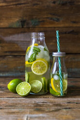 Glasflaschen mit aufgegossenem Wasser mit Zitrone, Limette, Minzblättern und Eiswürfeln - GIOF02267