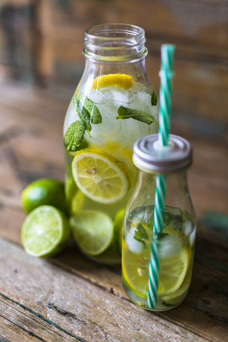 Glass bottles of infused water with lemon, lime, mint leaves and ice cubes stock photo