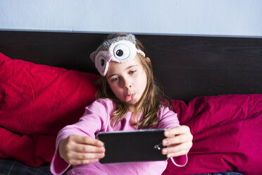 Mädchen auf dem Bett liegend nimmt Selfie mit Handy - XCF00151