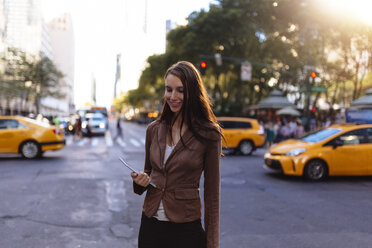 USA, New York, Manhattan, smiling young businesswoman with tablet on the street - BOYF00713