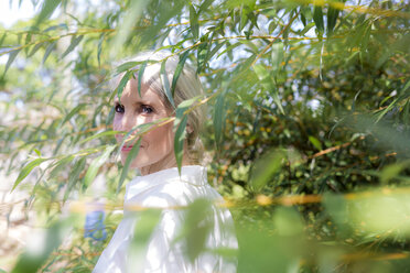 Porträt einer lächelnden Frau hinter Zweigen - GIOF02285