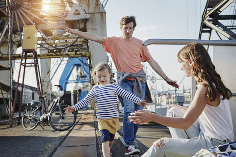 Deutschland, Hamburg, Vater und Tochter balancieren auf der Reling am Hafen, lizenzfreies Stockfoto