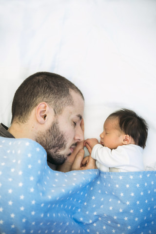 Vater schläft neben seinem neugeborenen Mädchen, lizenzfreies Stockfoto