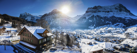 Schweiz, Kanton Bern, Grindelwald, Stadtbild im Winter bei Sonnenaufgang mit Maettenberg, Mittelhorn und Wetterhorn, lizenzfreies Stockfoto