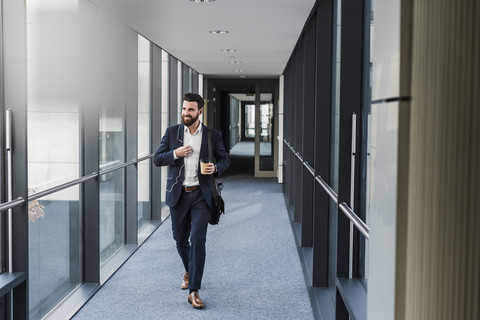 Businessman with earphones talking on smart phone in office building stock photo