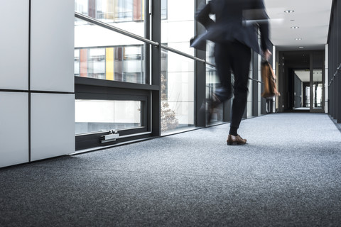 Geschäftsmann läuft im Korridor eines Bürogebäudes, lizenzfreies Stockfoto