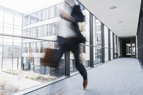 Geschäftsmann läuft im Korridor eines Bürogebäudes - UUF10177