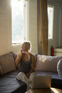 Blonde Frau am Telefon sitzt auf der Couch - KNTF00811