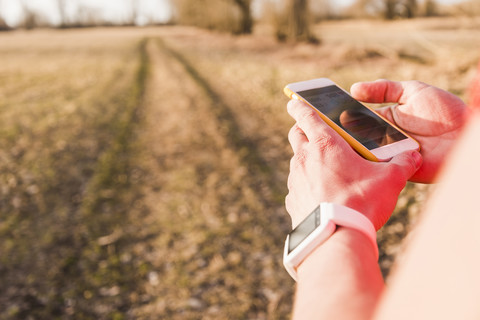 Sportler in ländlicher Umgebung, der Daten auf seinem Handy überprüft, lizenzfreies Stockfoto