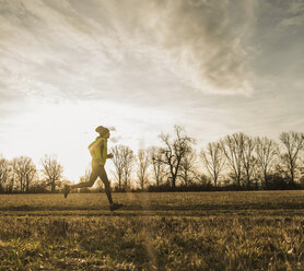 Mann läuft in ländlicher Landschaft bei Sonnenuntergang - UUF10225
