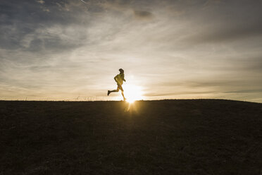Mann läuft in ländlicher Landschaft bei Sonnenuntergang - UUF10228