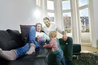 Parents with baby girl using laptop on couch - FMKF03599