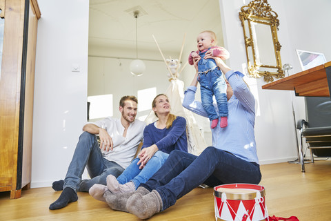 Glückliche Familie mit spielendem Mädchen im Wohnzimmer, lizenzfreies Stockfoto