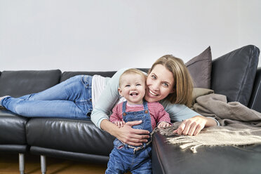 Glückliche Mutter und kleines Mädchen zu Hause auf der Couch - FMKF03617