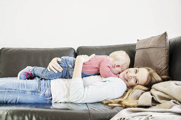 Glückliche Mutter und kleines Mädchen auf der Couch liegend - FMKF03620