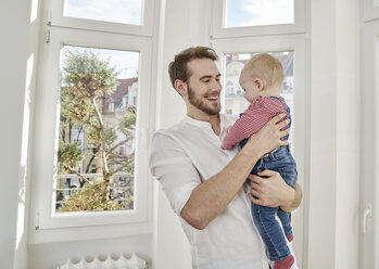 Father holding baby girl at the window - FMKF03622