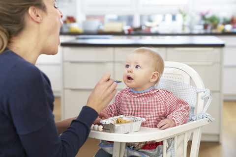 Mutter füttert kleines Mädchen, lizenzfreies Stockfoto