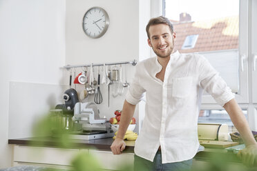 Portrait of smiling young man in kitchen - FMKF03641