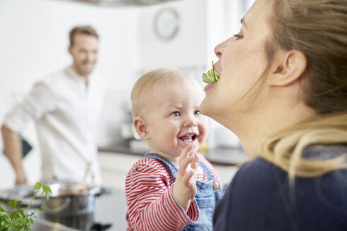 Mutter mit kleinem Mädchen in der Küche beim Essen von Kräutern - FMKF03643